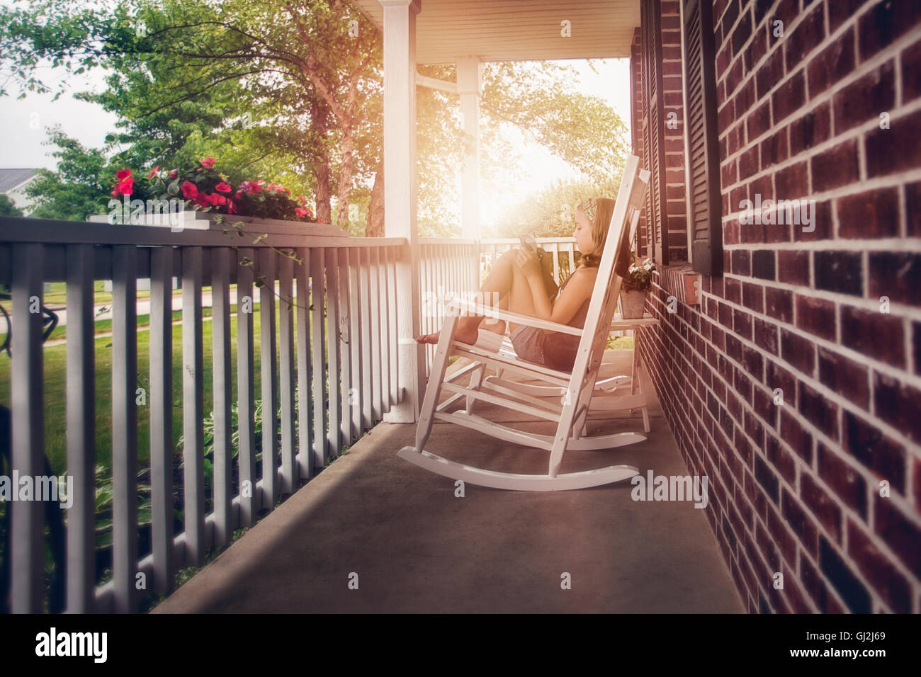 Ragazze sulla veranda in sedia a dondolo con tavoletta digitale Foto Stock