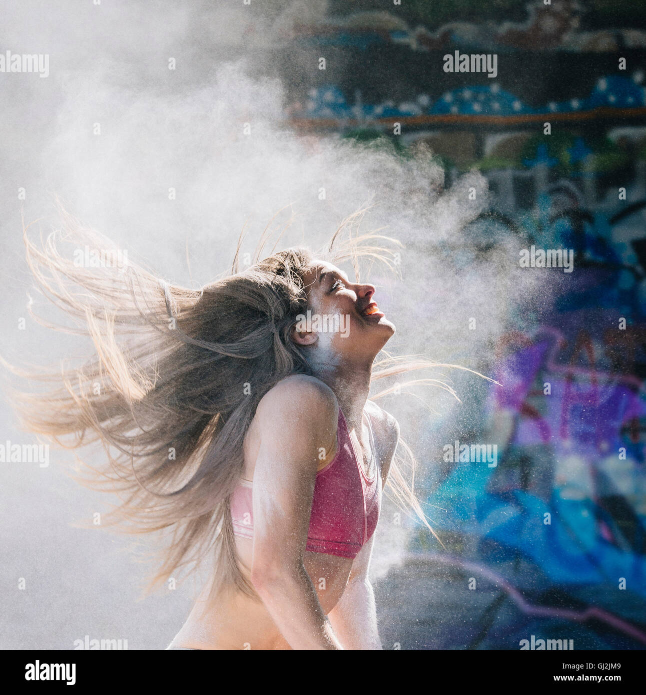 Donna di gettare polvere oggetto capelli indietro sorridente Foto Stock