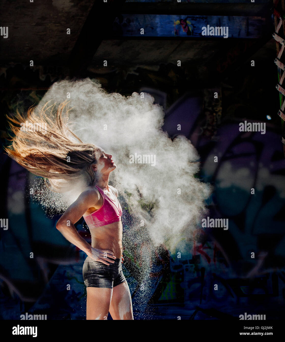 Donna in piedi con le mani sui fianchi di gettare polvere oggetto capelli indietro Foto Stock