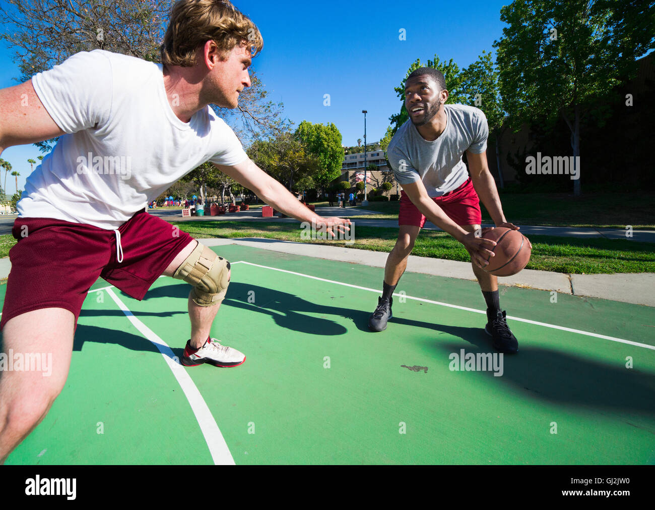 Due uomini giocare a basket sulla corte esterna Foto Stock