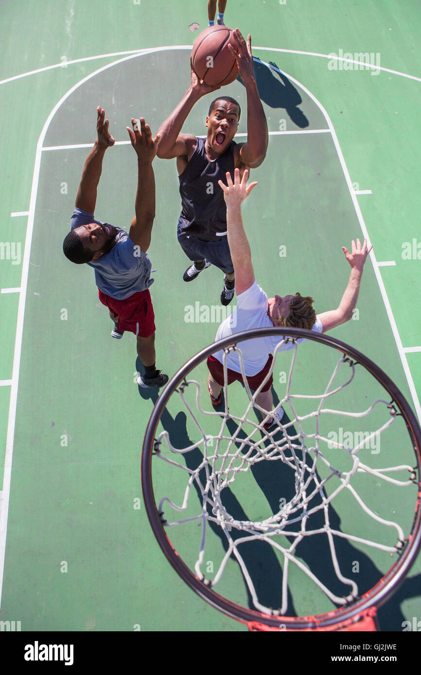 Gruppo di amici maschi giocare a basket sulla corte esterna, vista in elevazione Foto Stock