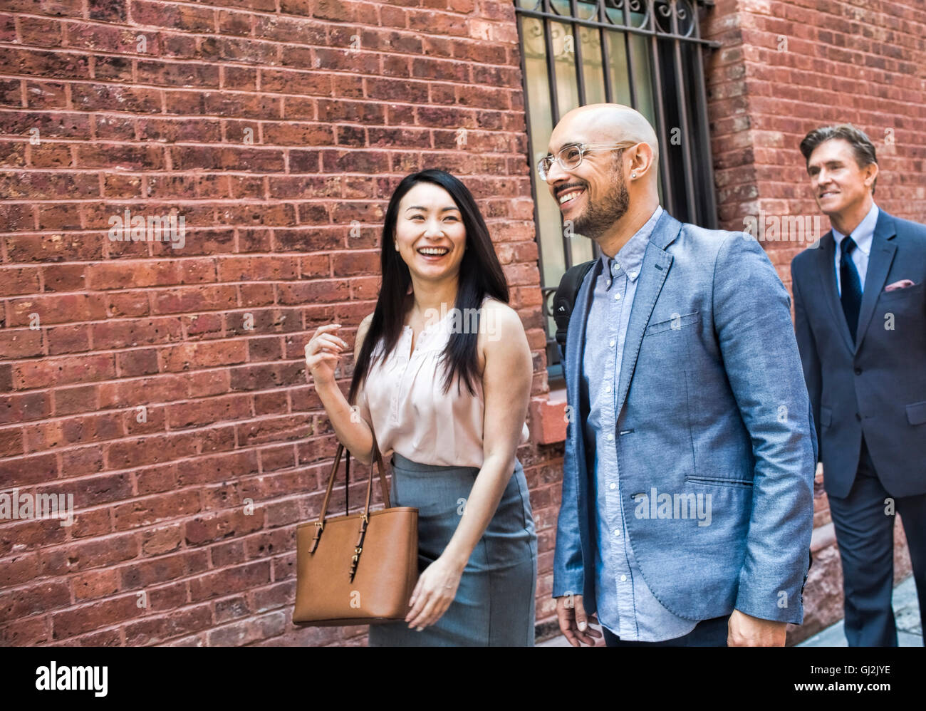 Imprenditore e la donna camminare insieme in street, sorridente Foto Stock