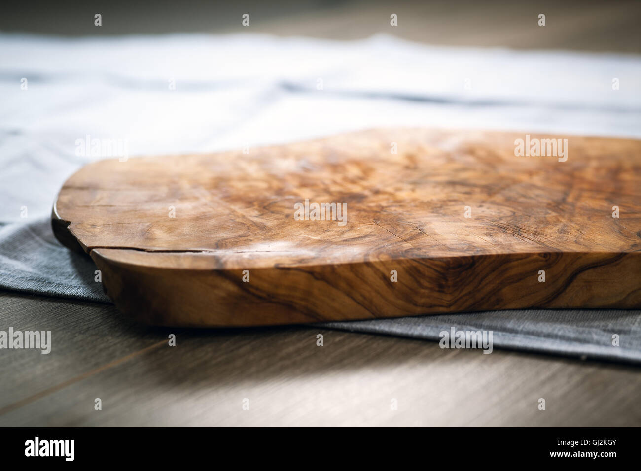 Tagliere in legno realizzato dal legno d'ulivo sul tavolo blu panno Foto Stock