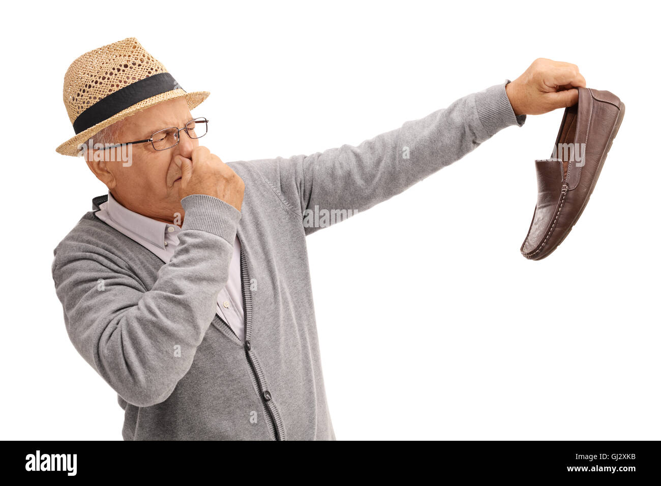 Disgustato vecchio uomo tenendo un puzzolente calzatura isolati su sfondo bianco Foto Stock