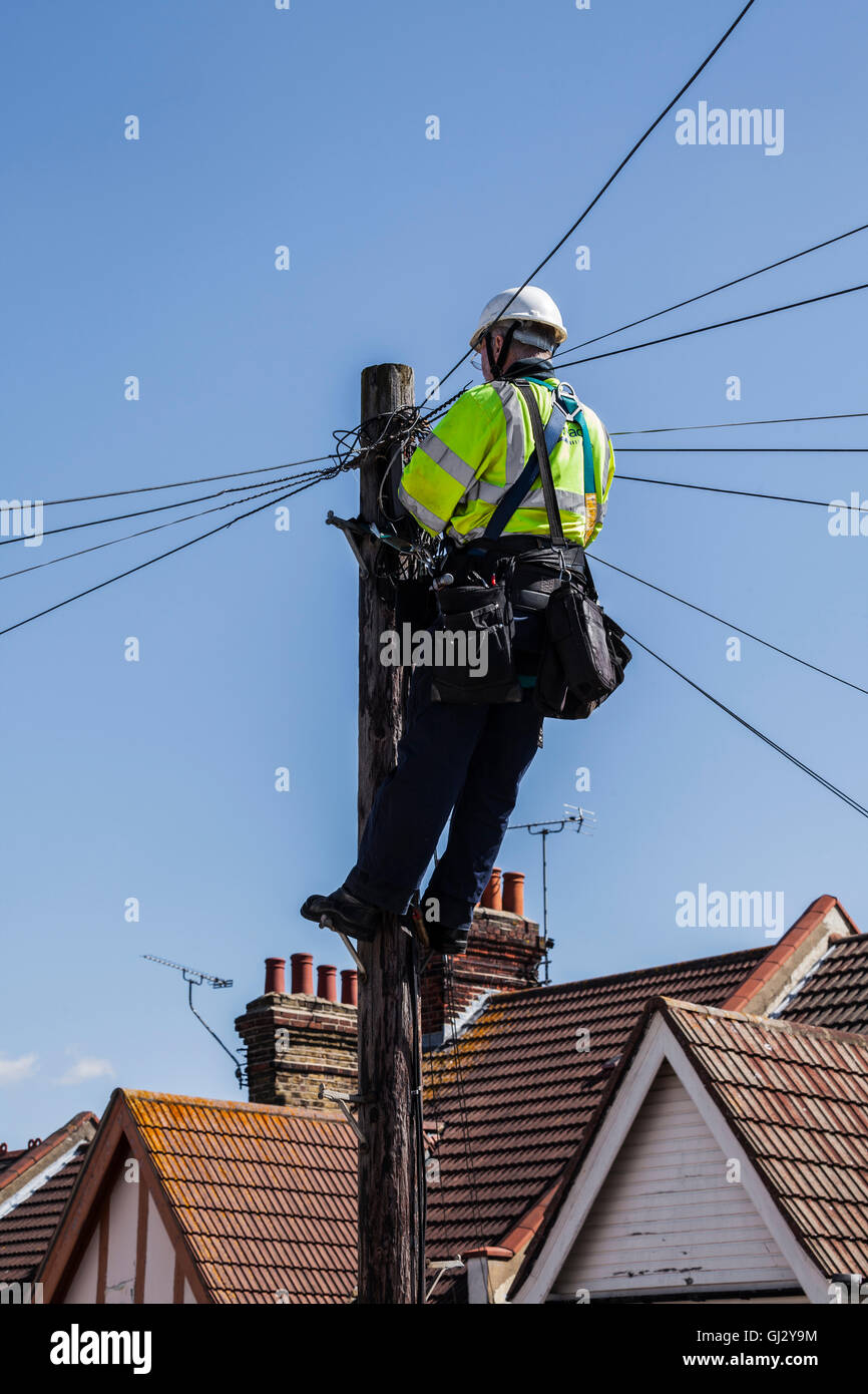 BT ingegnere di lavoro sui fili del telefono alla sommità di un palo Foto Stock