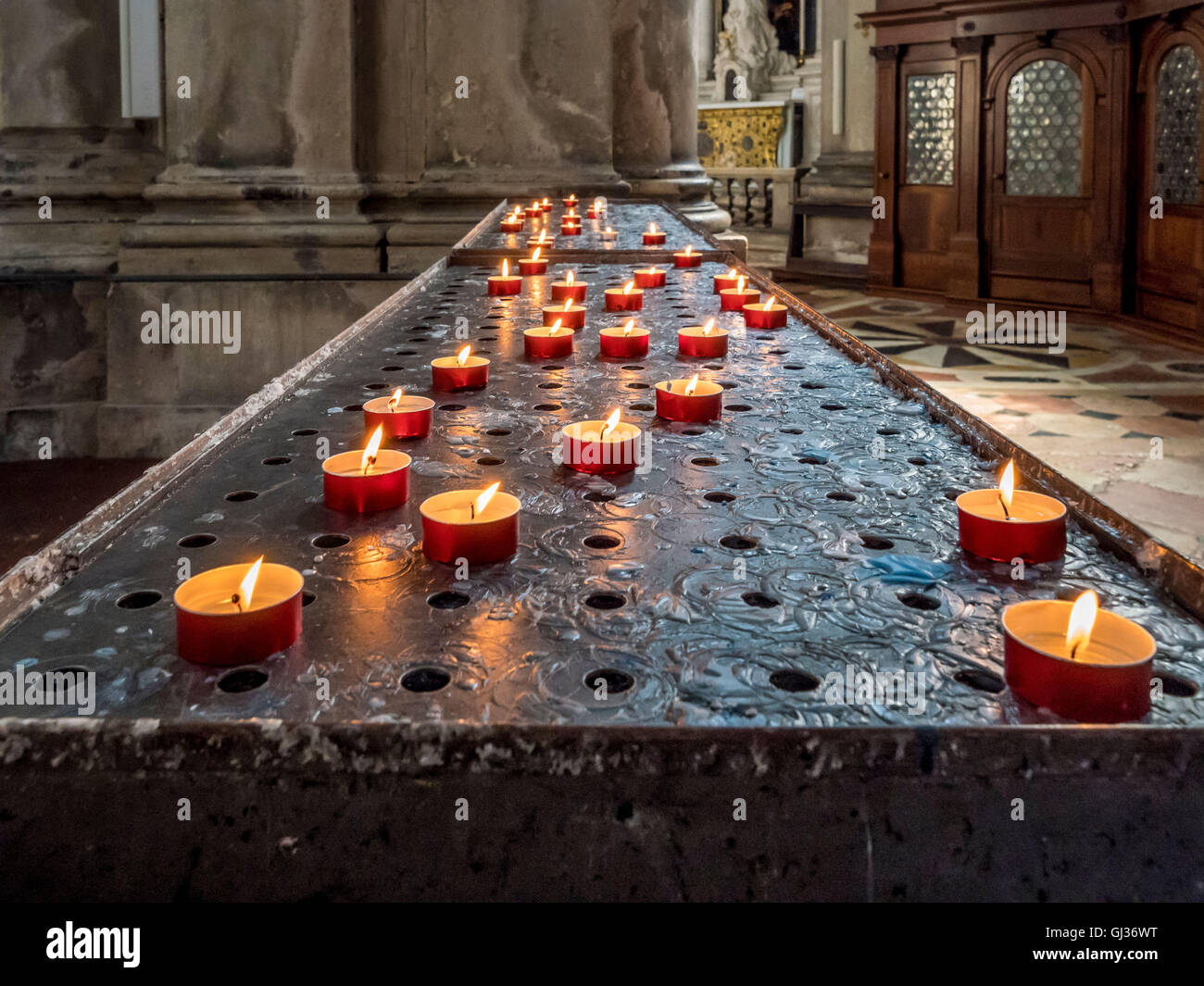 Preghiera o candele votive bruciando all interno della chiesa di Santa Maria della Salute, Venezia, Italia. Foto Stock