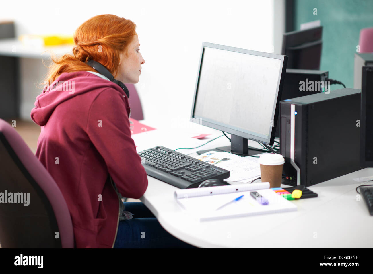 Femmina giovane studente di college alla scrivania del computer di lettura Foto Stock
