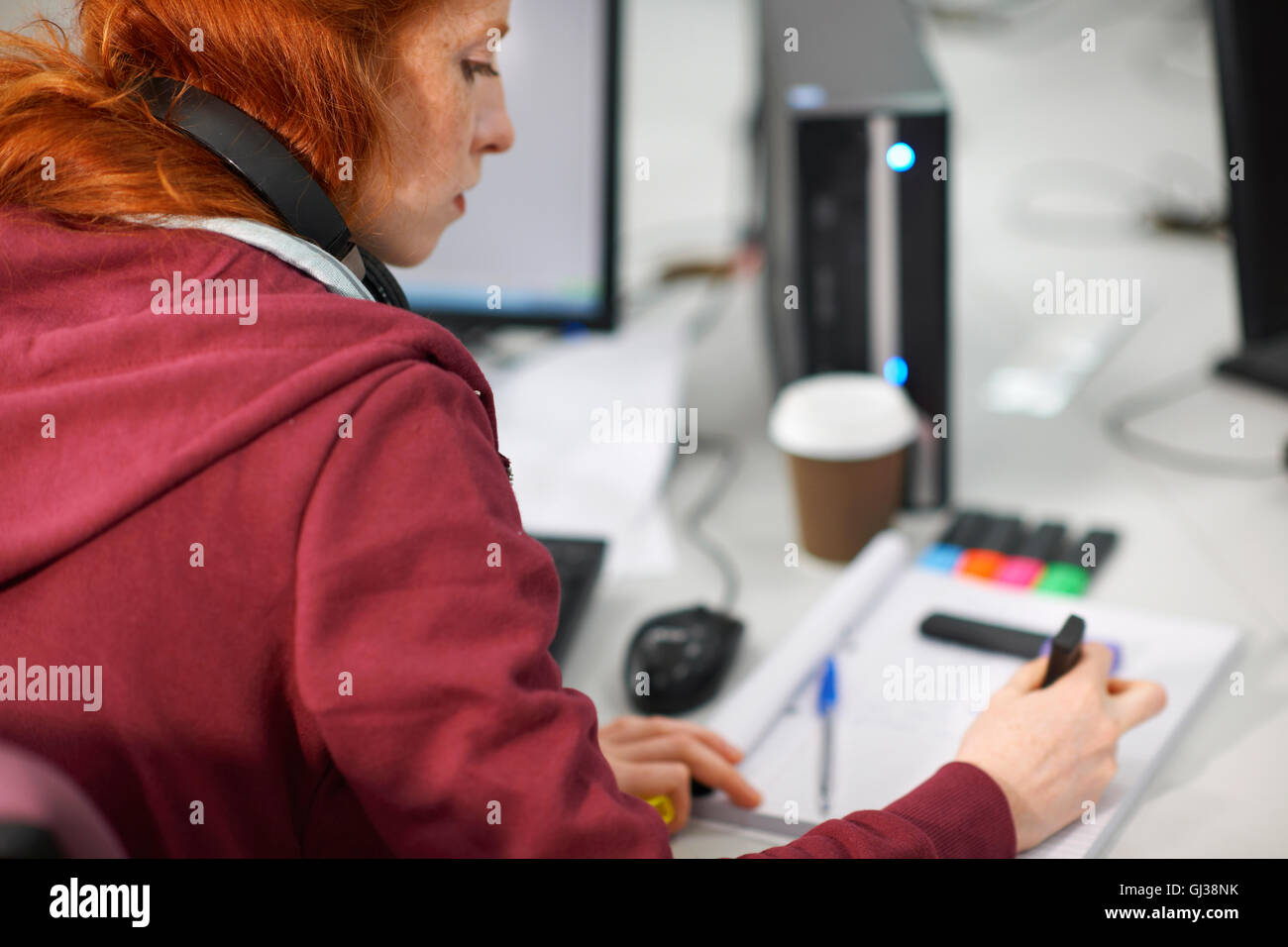 Femmina giovane studente di college a computer desk rendendo note Foto Stock