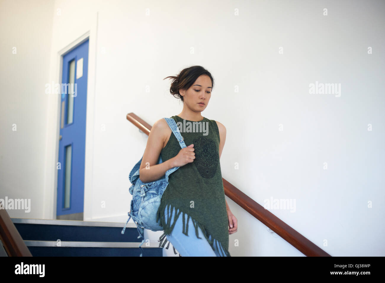 Femmina giovane studente di college si sta spostando verso il basso le scale Foto Stock