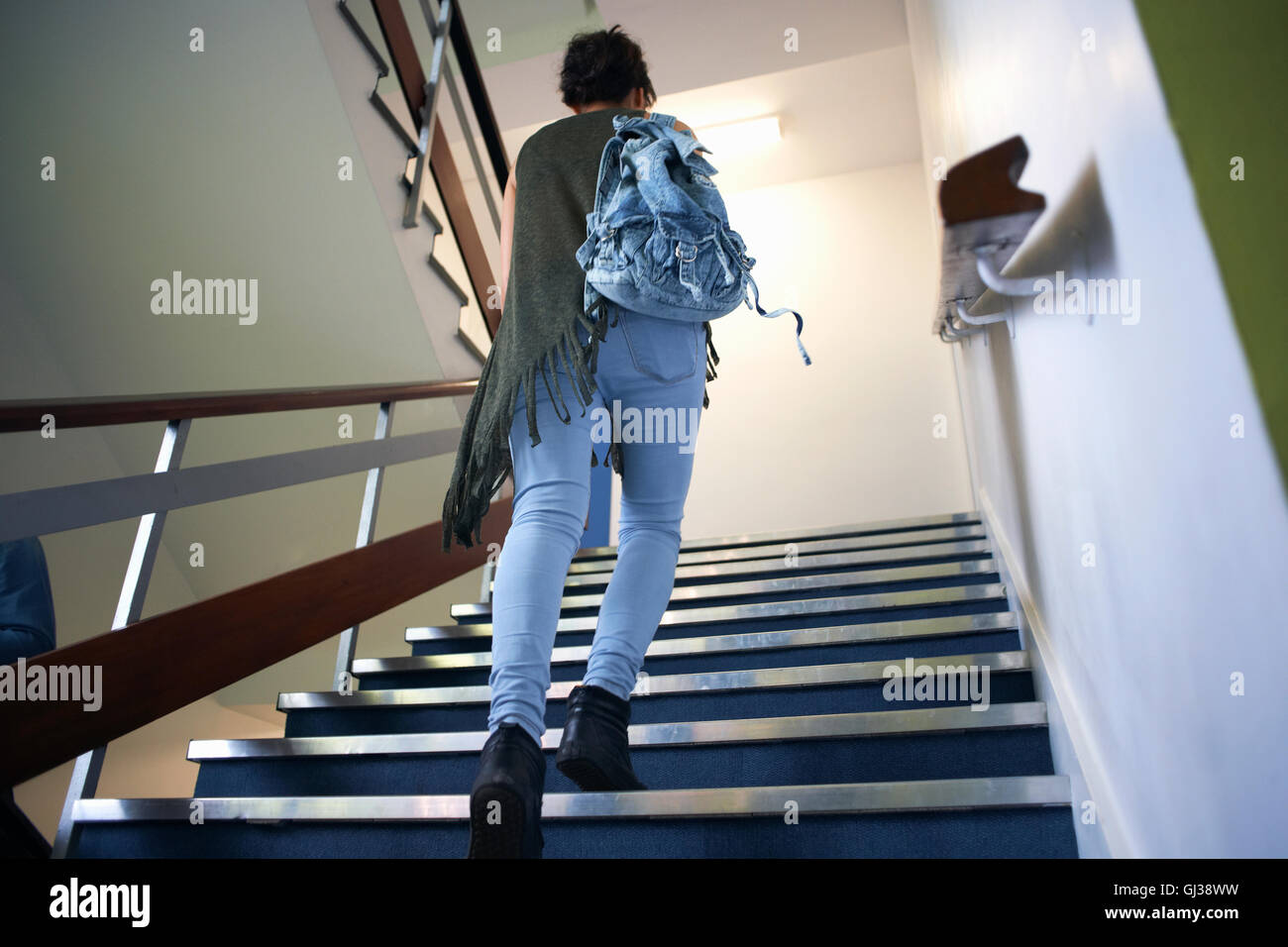 Femmina giovane studente di college spostamento verso l'alto di Scala Foto Stock