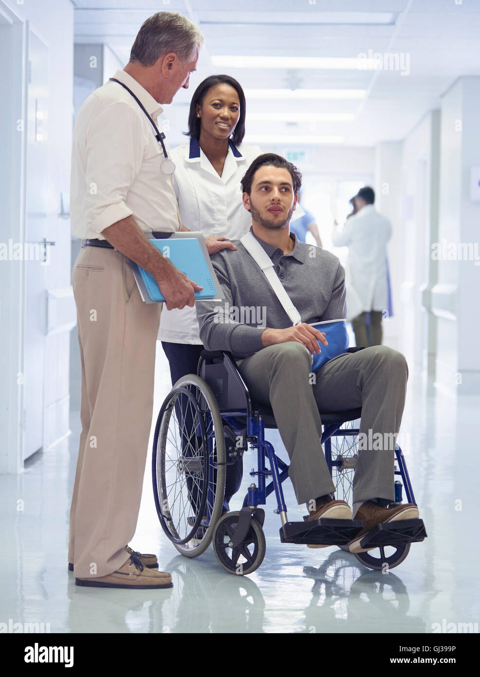 Consulenza medico con uomo in sedia a rotelle con imbracatura del braccio Foto Stock