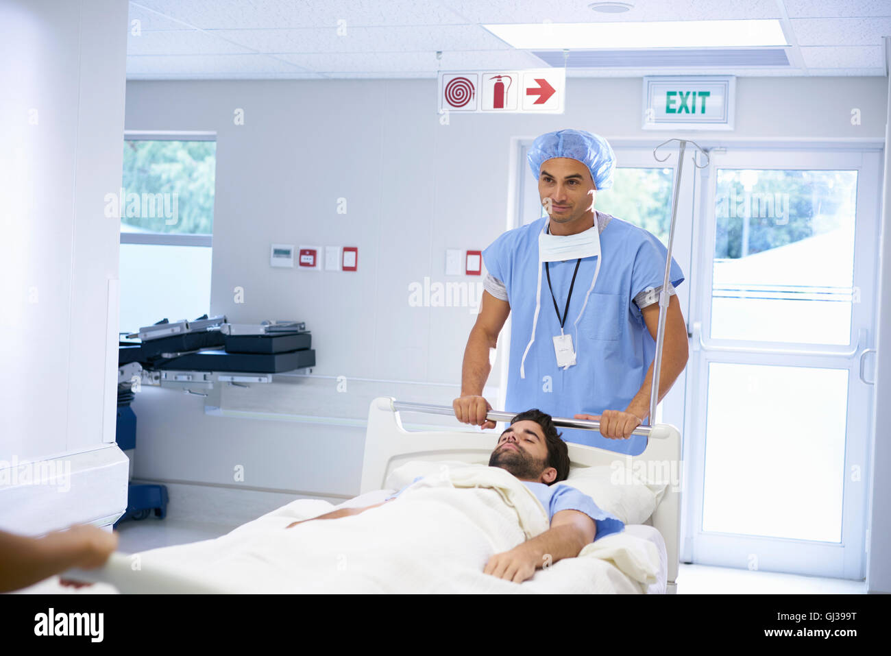 I medici che indossa scrub chirurgico spingendo il paziente sul letto di ospedale Foto Stock