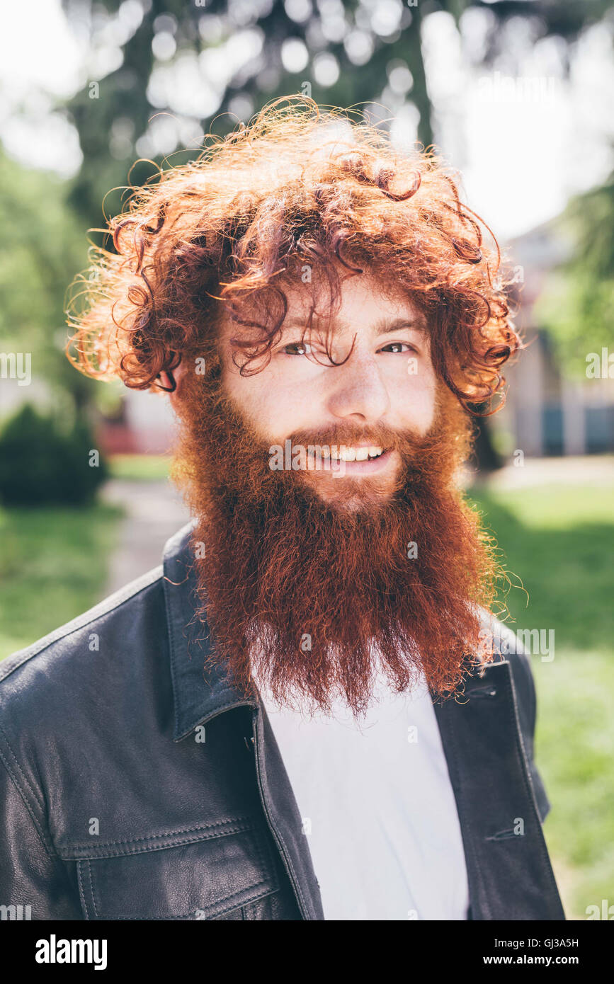 Ritratto di giovane maschio hipster con ricci capelli rossi e la barba in posizione di parcheggio Foto Stock