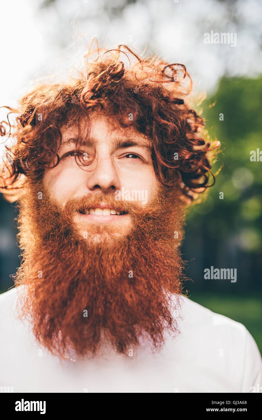 Ritratto di giovane maschio hipster con ricci capelli rossi e la barba in posizione di parcheggio Foto Stock