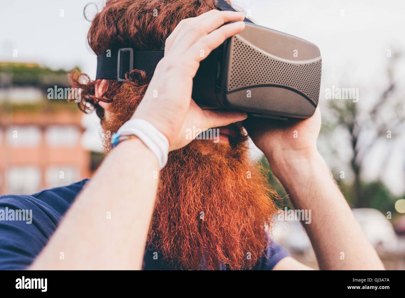 Giovane maschio hipster con i capelli rossi e la barba che indossa la realtà virtuale auricolare Foto Stock