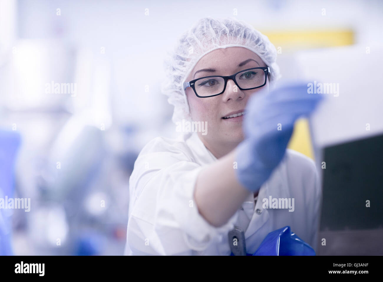 Operaio di fabbrica indossando retina per capelli guardando la documentazione Foto Stock