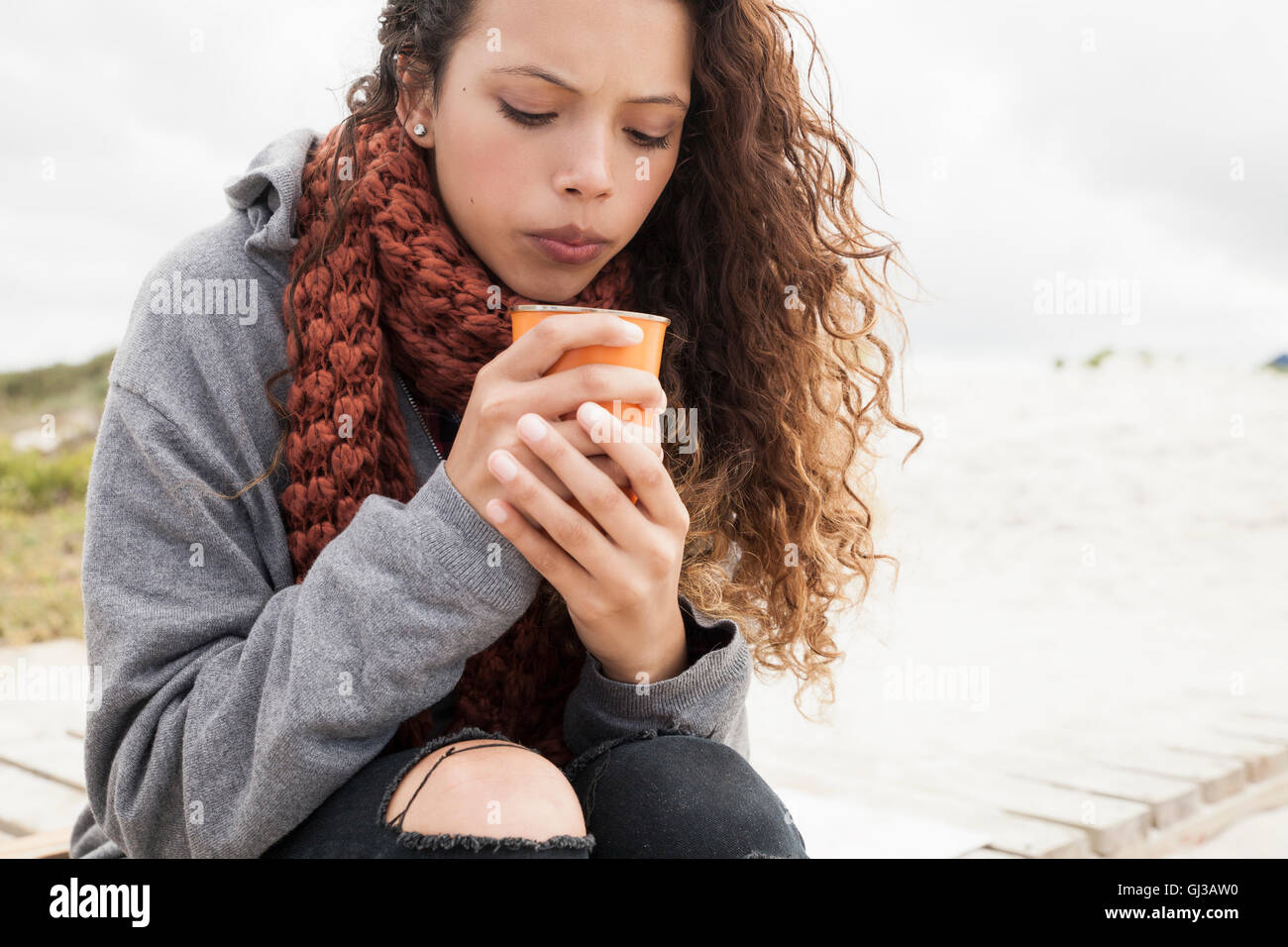 Giovane donna insufflando nella tazza di caffè sul freddo giorno Foto Stock