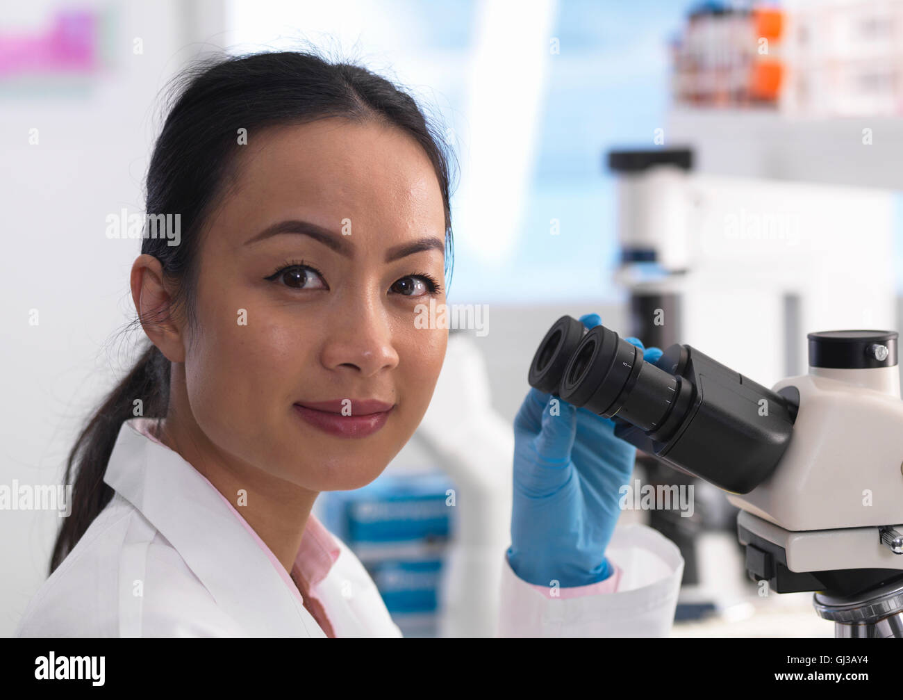 Scienziato visualizzazione di un vetrino di vetro contenente un campione per analisi di laboratorio Foto Stock