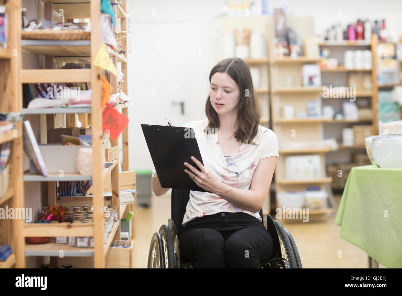 Giovani femmine shop assistant utilizzando inventario di sedie a rotelle in negozio Foto Stock