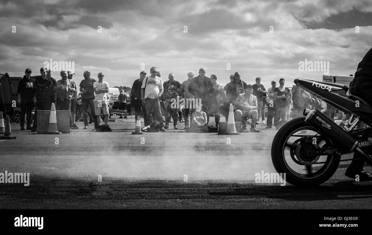Spettatori guarda un concorrente burnout il suo pneumatico,riscaldamento per ottenere la trazione, prima di una drag racing event. Foto Stock
