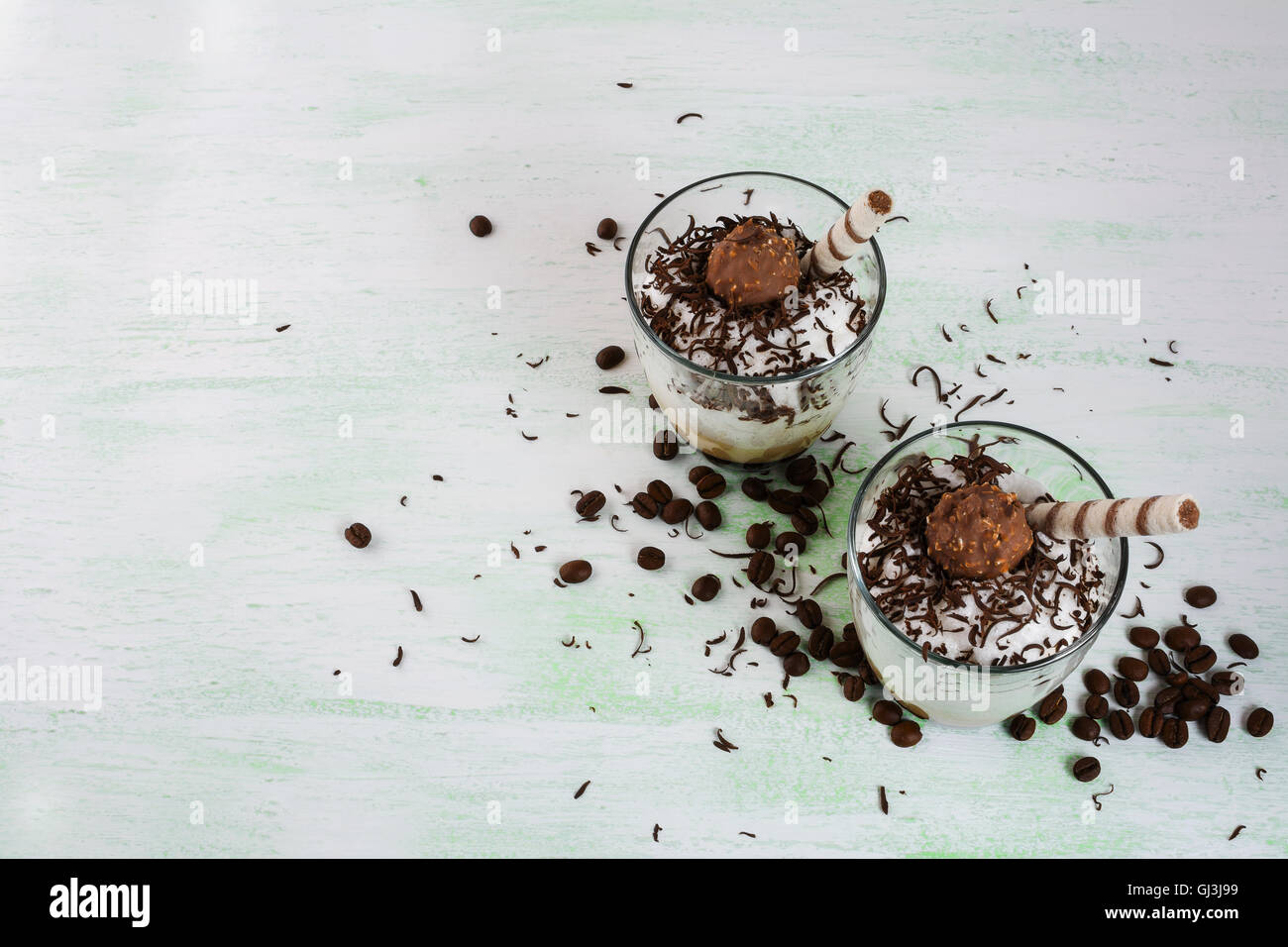 Frullato di caffè con panna montata su sfondo verde chiaro. Cioccolato cocktail cremoso con cacao. Foto Stock