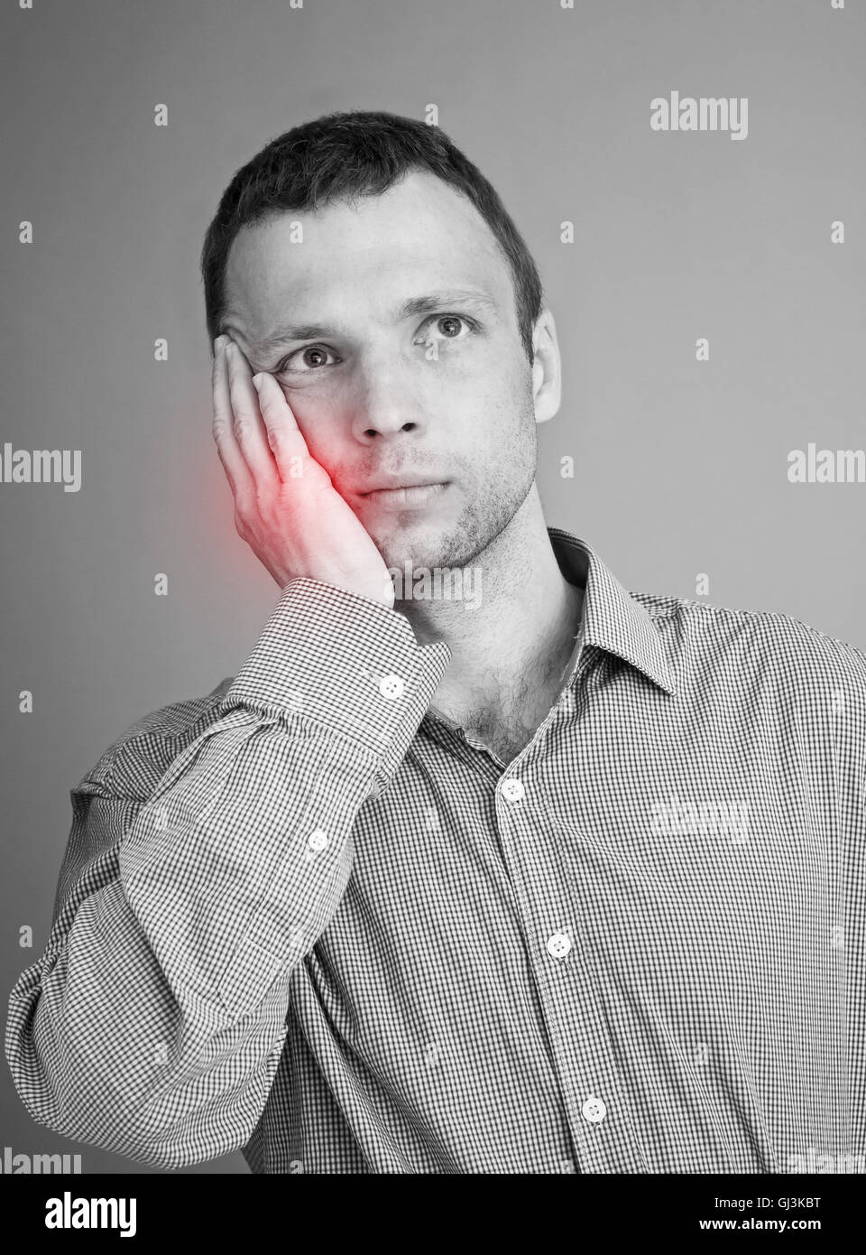 Giovane uomo caucasico con il mal di denti. Bianco e nero foto stilizzata con rosso ache locale spot Foto Stock