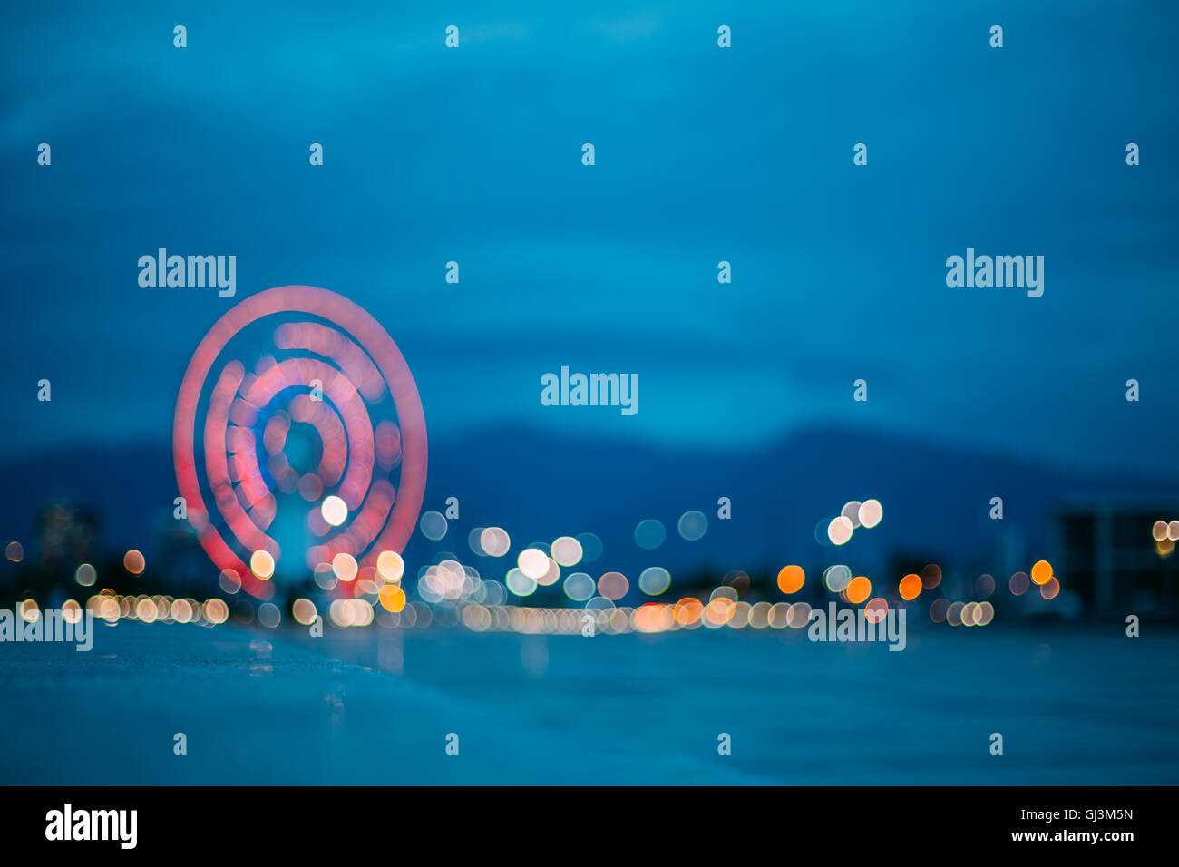 Abstract sfocatura di immagine colorata luminosamente illuminata ruota panoramica Ferris nella città di divertimenti Parco su nero blu del cielo della sera Bokeh di fondo Foto Stock