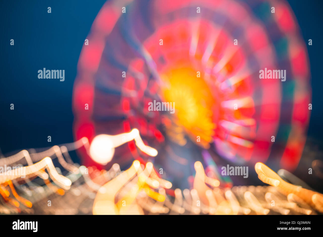 Abstract sfocatura di immagine colorata luminosamente illuminata ruota panoramica Ferris nella città di divertimenti Parco su nero blu del cielo della sera Bokeh di fondo Foto Stock