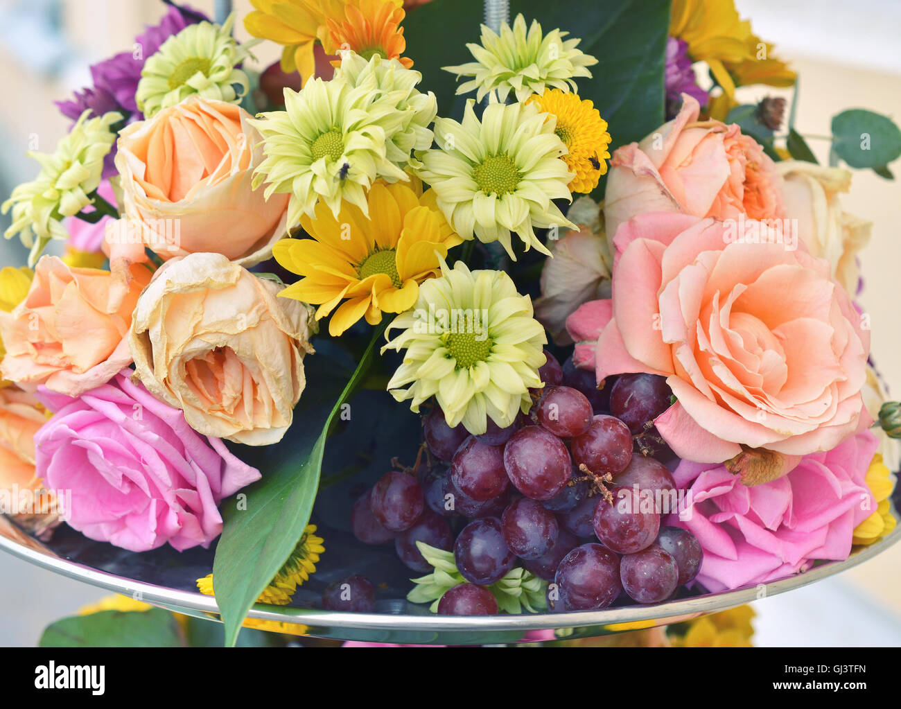 Composizione di fiori con uve, rose e gerbere. Foto Stock