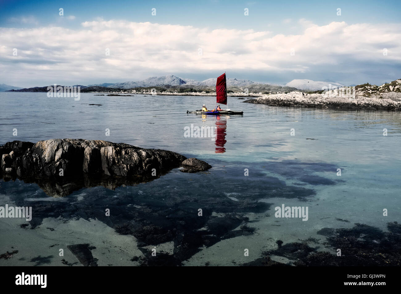 Un rosso barca a vela in una baia idilliaca sul Arisaig della costa ovest della Scozia Foto Stock