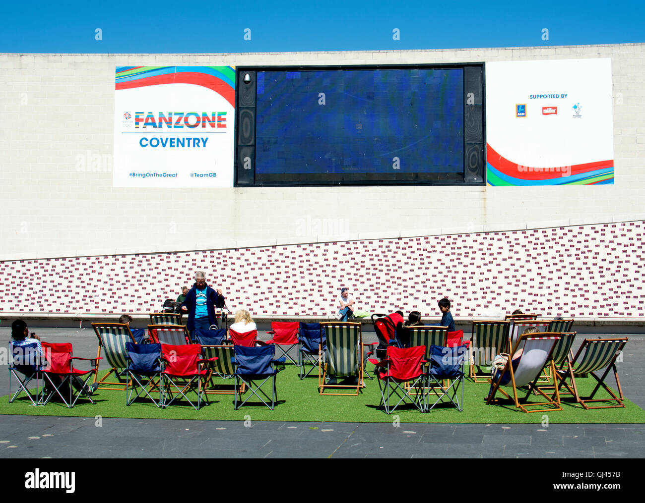 Coventry, Regno Unito. 12 Agosto, 2016. Regno Unito Meteo. Persone godere il caldo clima soleggiato mentre guardando il grande schermo nel Rio Olimpiadi Fanzone in luogo del millennio in Coventry city centre. Credito: Colin Underhill/Alamy Live News Foto Stock