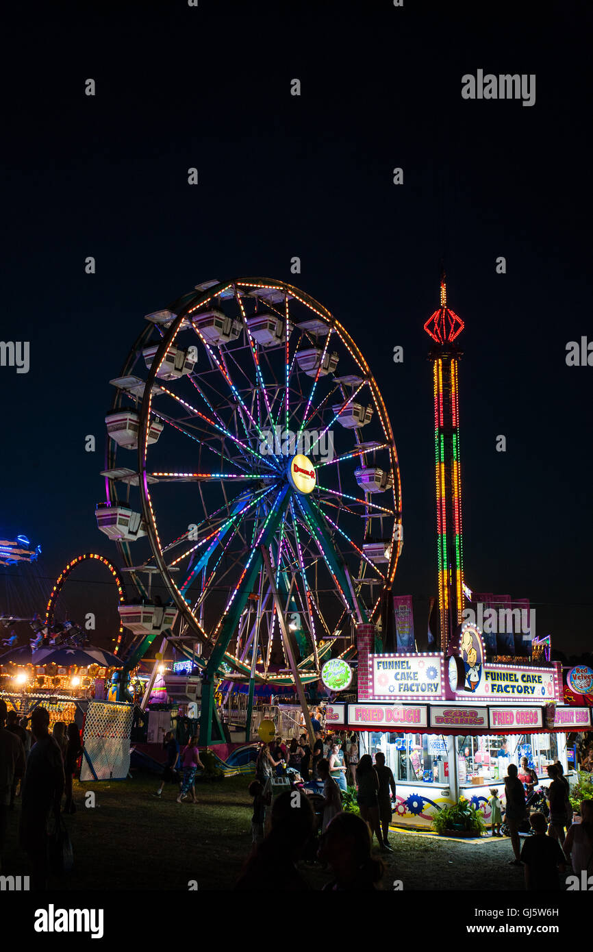 Ruota panoramica illuminata dai colori vivaci e giostre di carnevale sono colorate attrazioni notturne alla fine della fiera estiva della contea di Cecil Co., Maryland, USA. Foto Stock