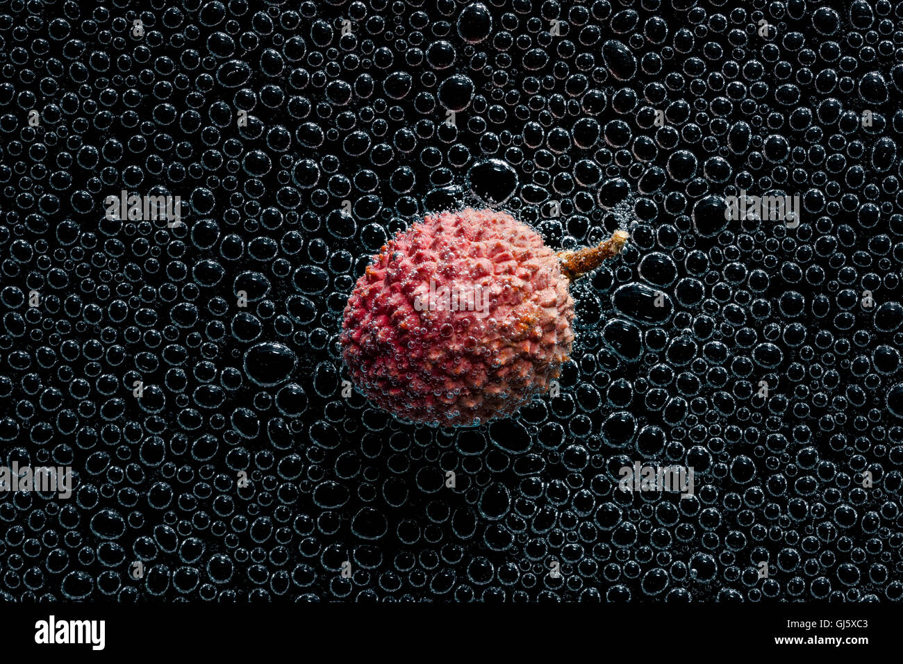 Il Lychee (Litchi) frutta in acqua minerale, una serie di foto. Close-up di acqua gassata su sfondo nero Foto Stock