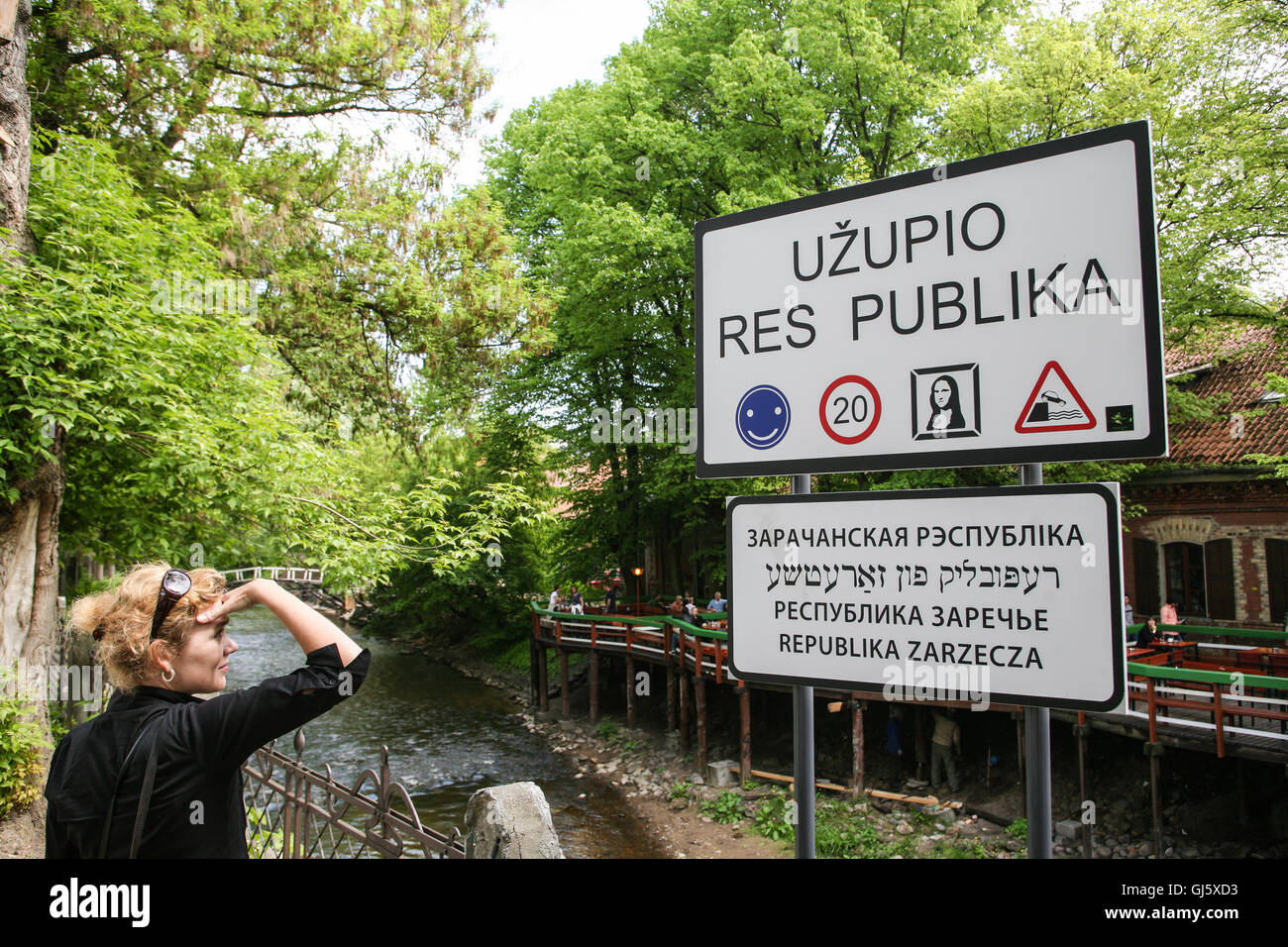 Uzupio statualità signpost, sulle rive del fiume Vilnia, con Uzupio Kavine cafe sull'altra banca. In una zona di Vilnius kn Foto Stock