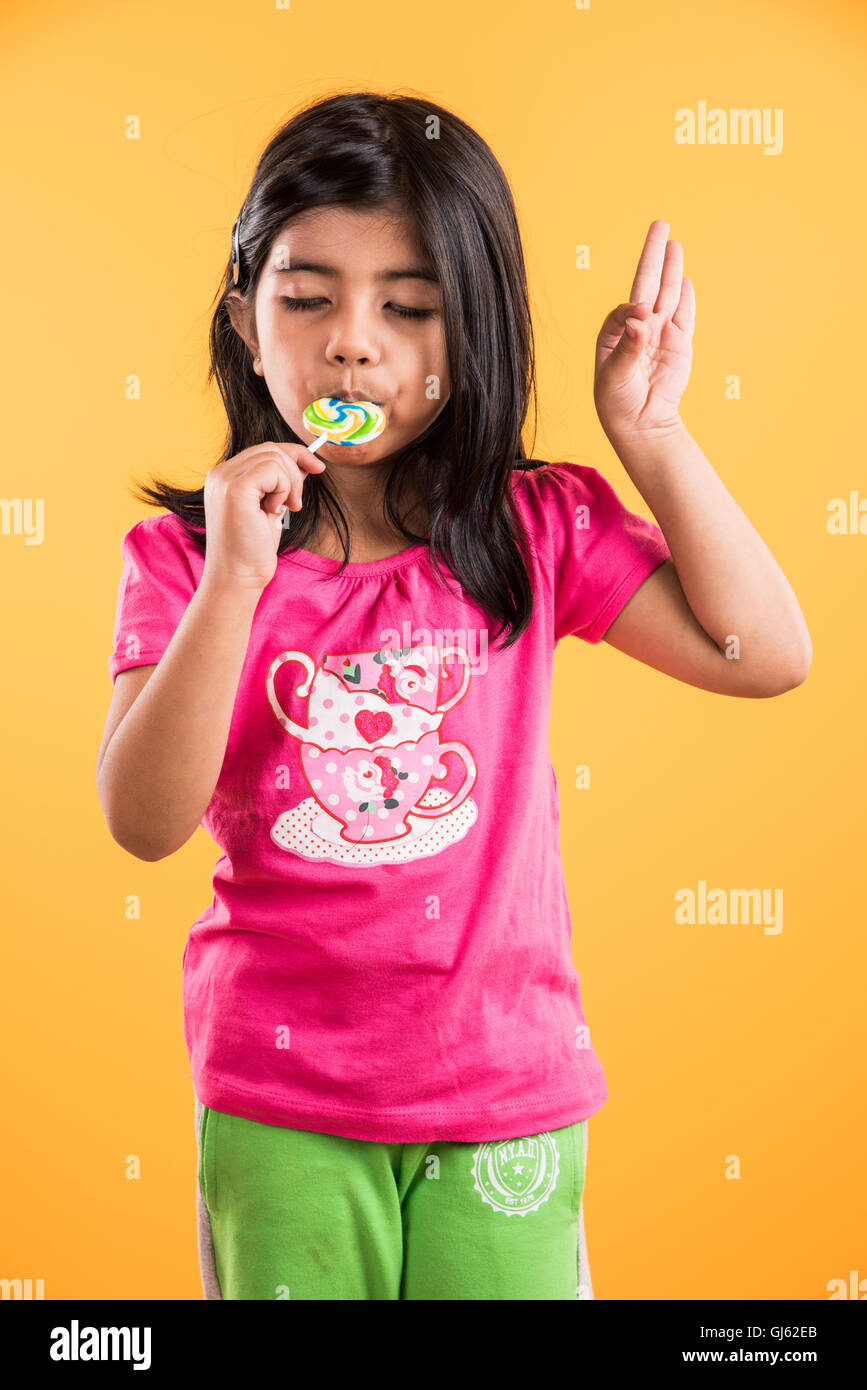 Indian piccola ragazza con lolipop o loly pop, ragazza asiatica e lolipop o lolypop, giocoso indiano ragazza carina che posano con lolipop Foto Stock