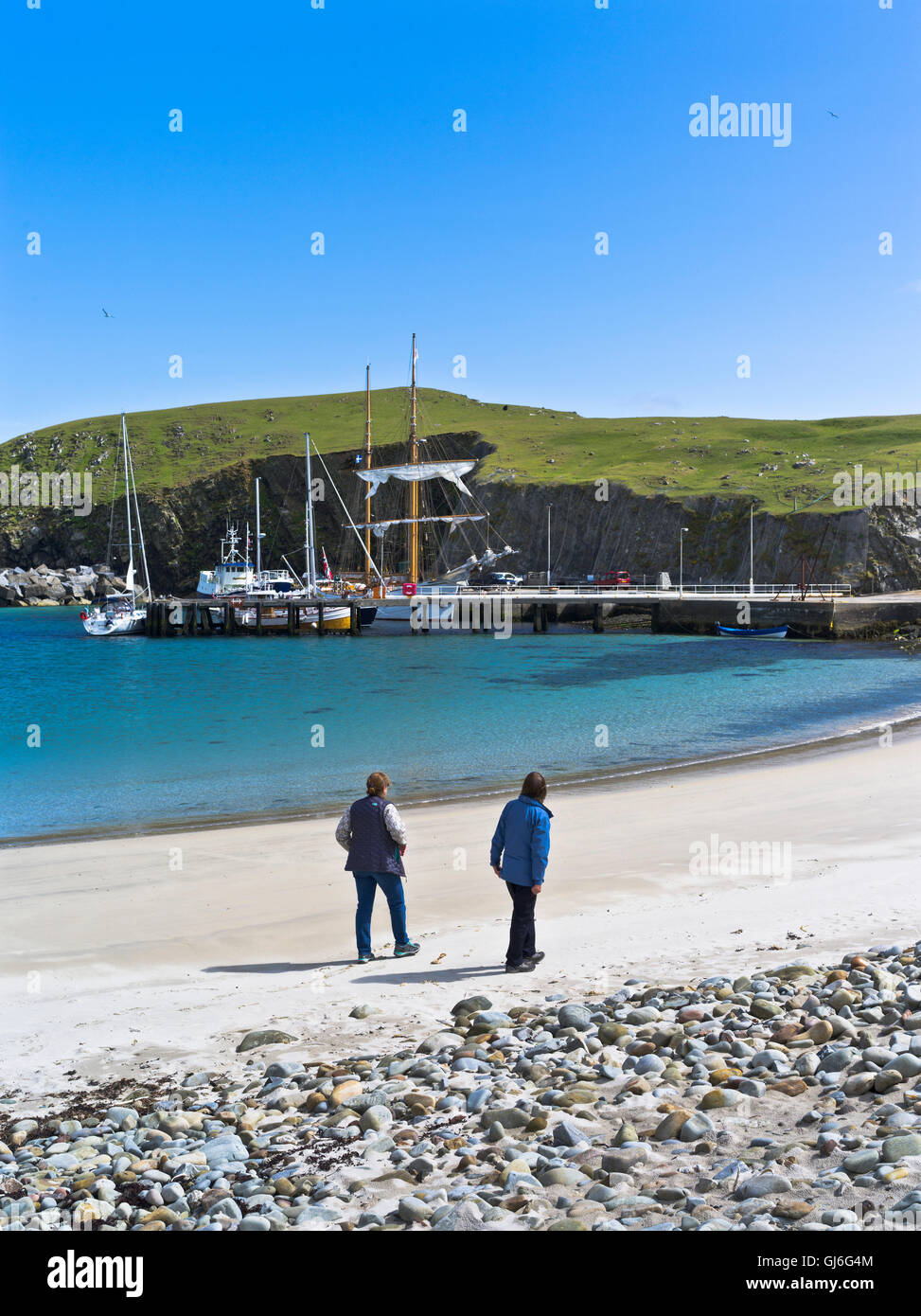 dh NORTH HAVEN FIERA ISLE donne turistiche a piedi spiaggia di sabbia barche alto yacht nave molo scozia isole persone Foto Stock