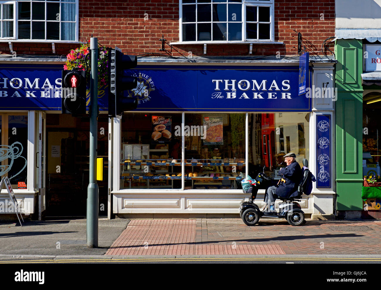 Thomas Baker shop e uomo sulla mobilità scooter, Driffield, East Yorkshire, Inghilterra, Regno Unito Foto Stock