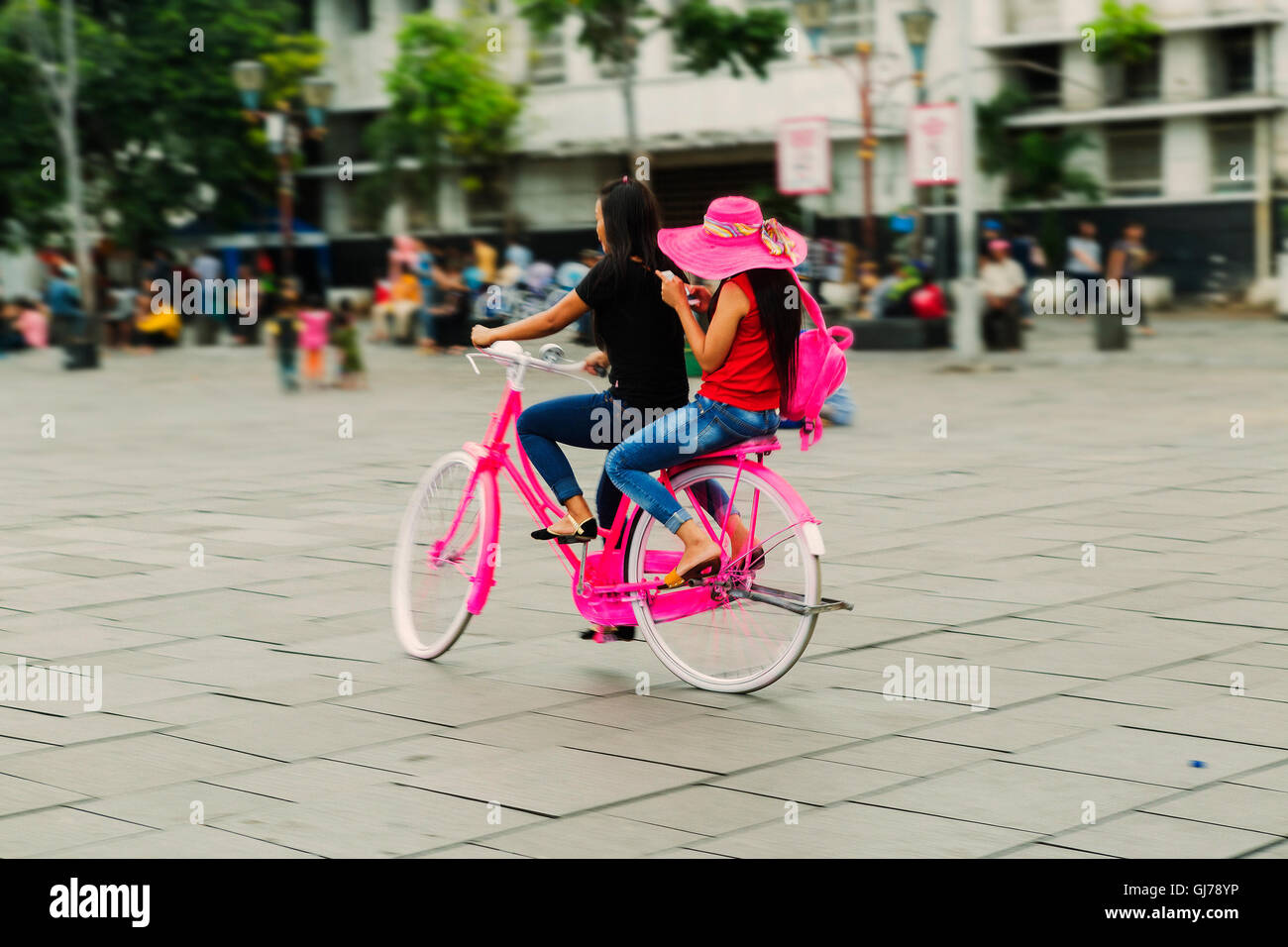 Due ragazze in rosa hat in bicicletta nella città di Jakarta. Le persone attive. All'aperto Foto Stock