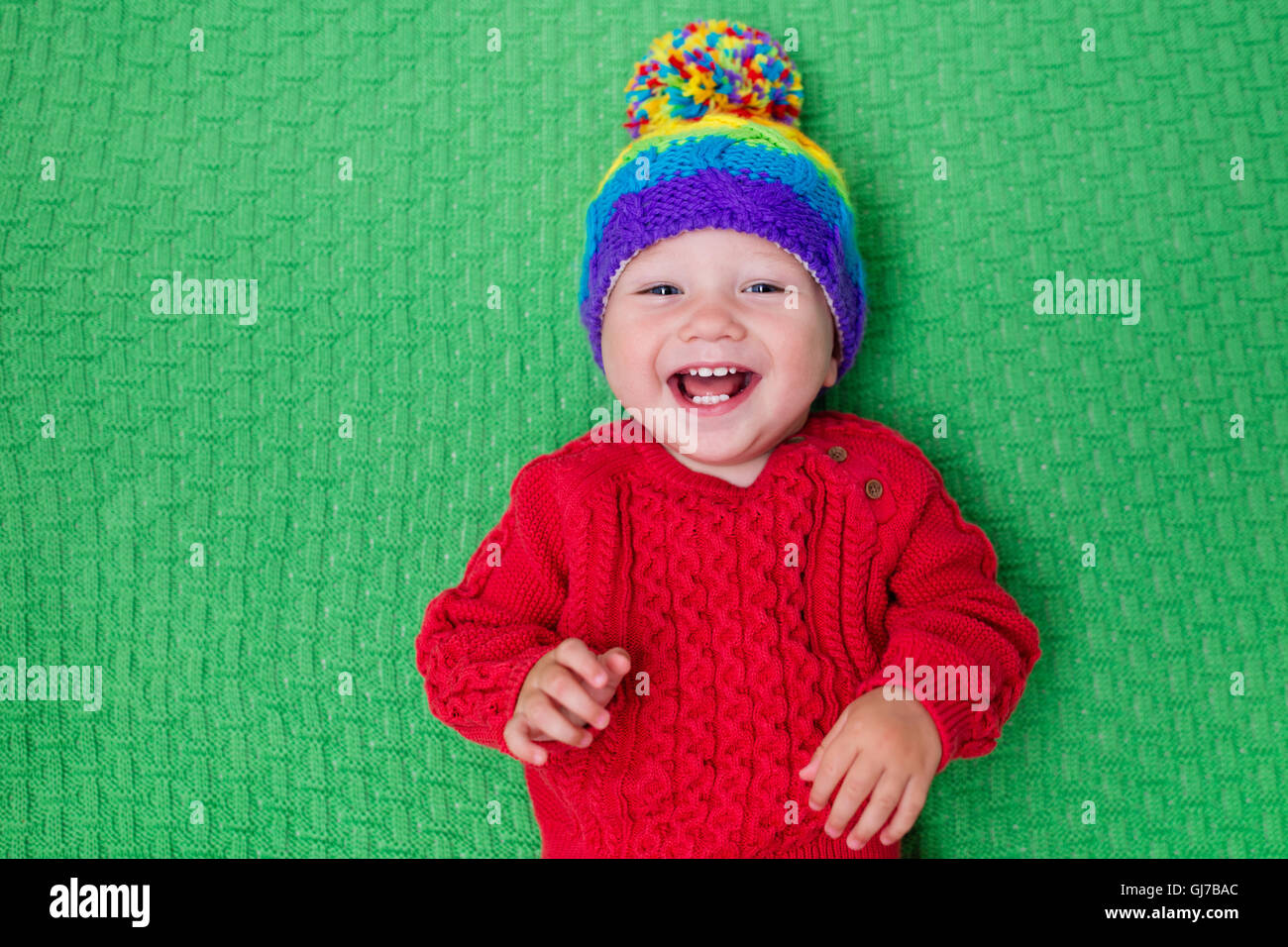 Carino baby in calda lana berretto lavorato a maglia su una coperta di rosso. Autunno e Inverno di abbigliamento per bambini piccoli. Maglieria colorata per i bambini. Foto Stock