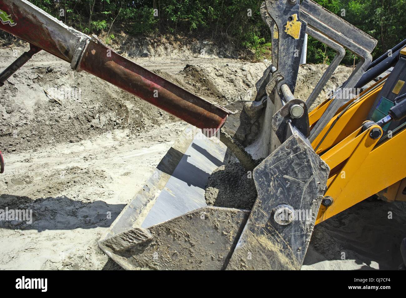 La commutazione del cemento liquido dal miscelatore in un cucchiaio scavatrice. Foto Stock