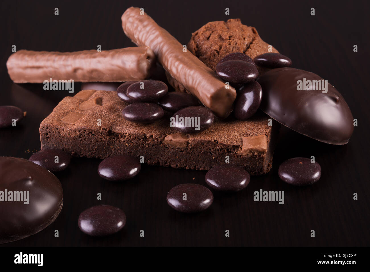 Varietà di dolci al cioccolato scuro su sfondo di legno Foto Stock