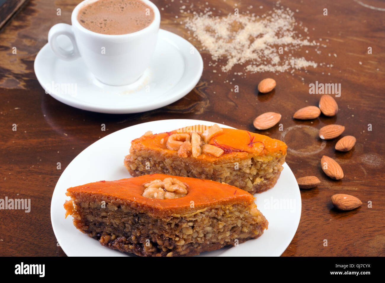Il baklava, una tazza di caffè nero e mandorle sulla tavola in bar o caffè vecchio tavolo Foto Stock