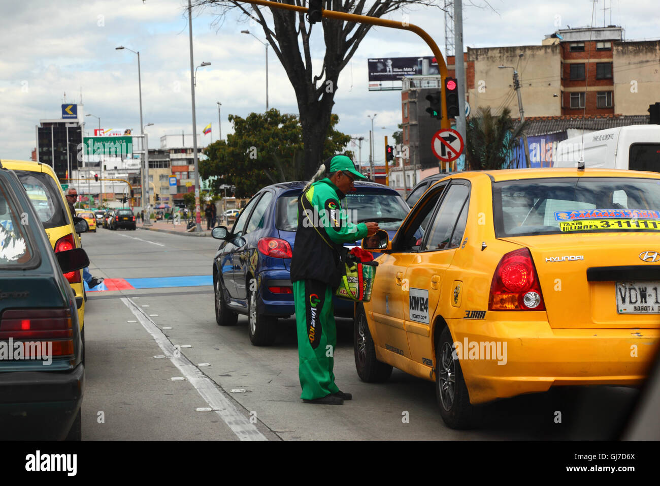 L'uomo vendita di barrette energetiche al tassista al semaforo, Bogotà, Colombia Foto Stock