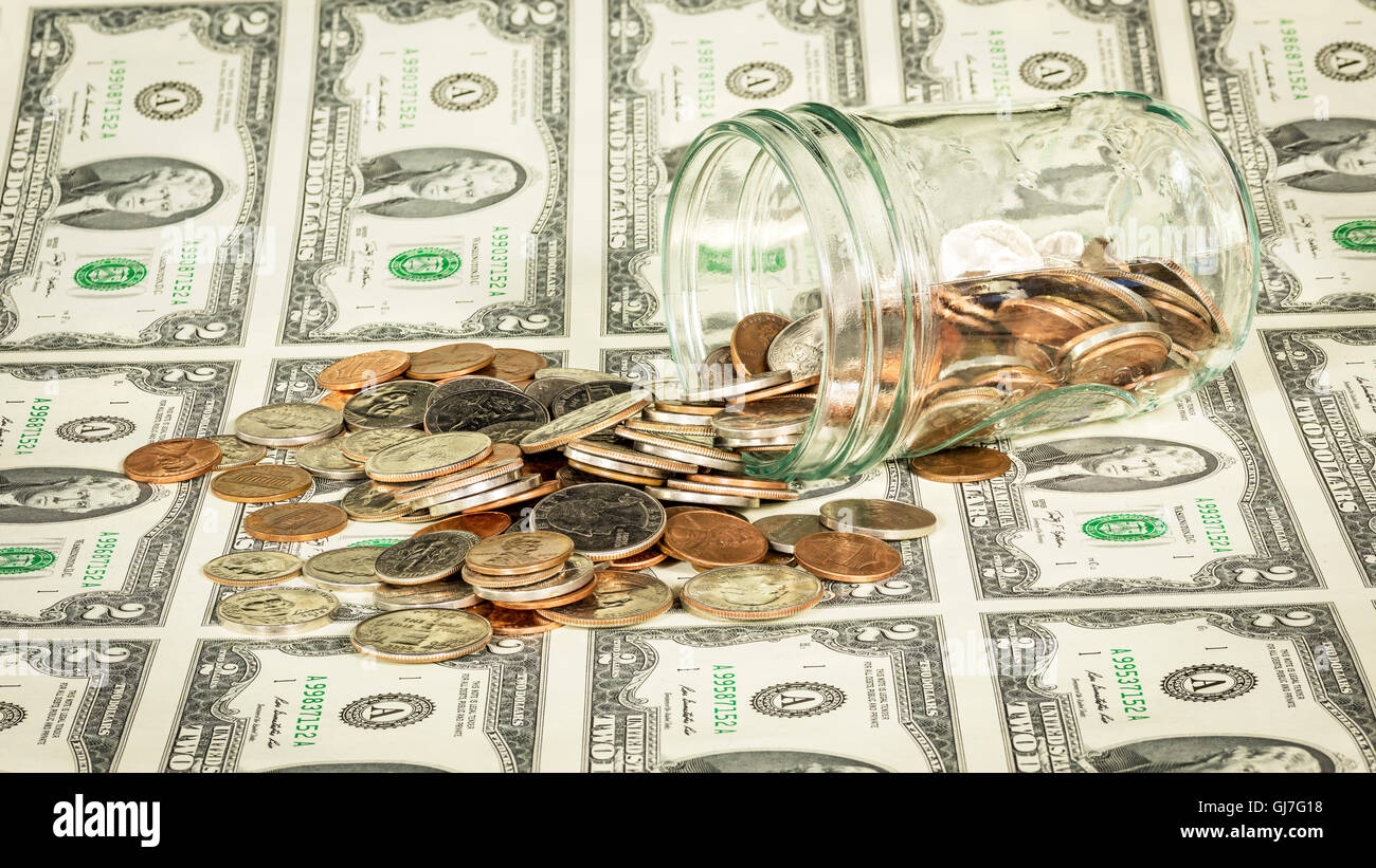 Foglio di due fatture del dollaro con un barattolo di monete Foto Stock
