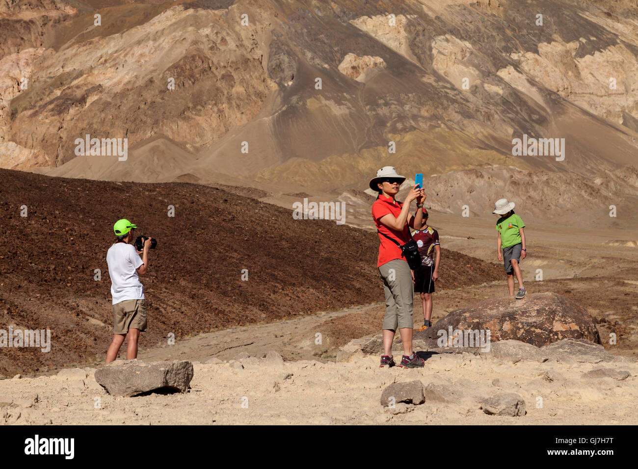 La donna a scattare foto di famiglia al vulcaniche e sedimentarie sulle colline vicino a artista della tavolozza in Parco nazionale della Valle della Morte, Calif Foto Stock