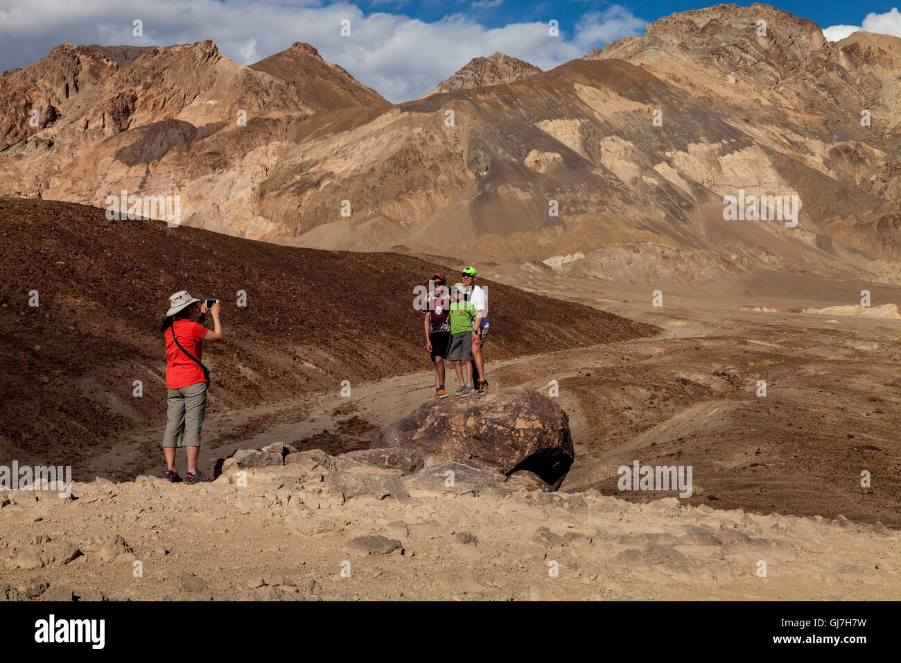 La donna a scattare foto di famiglia al vulcaniche e sedimentarie sulle colline vicino a artista della tavolozza in Parco nazionale della Valle della Morte, Calif Foto Stock