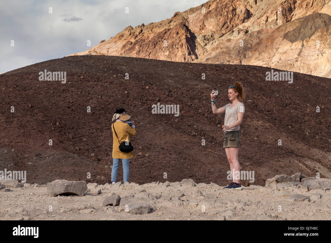 Donna prendendo selfies da vulcaniche e rocce sedimentarie sulle colline vicino a artista della tavolozza in Parco nazionale della Valle della Morte, CALIFORNIA, STATI UNITI D'AMERICA Foto Stock