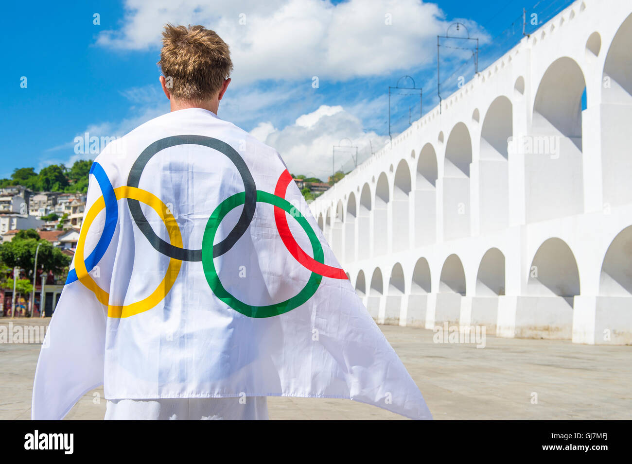 RIO DE JANEIRO - MARZO 06, 2015: atleta drappeggiati con bandiera olimpica si erge all'aperto nella plaza presso la famosa Lapa archi. Foto Stock