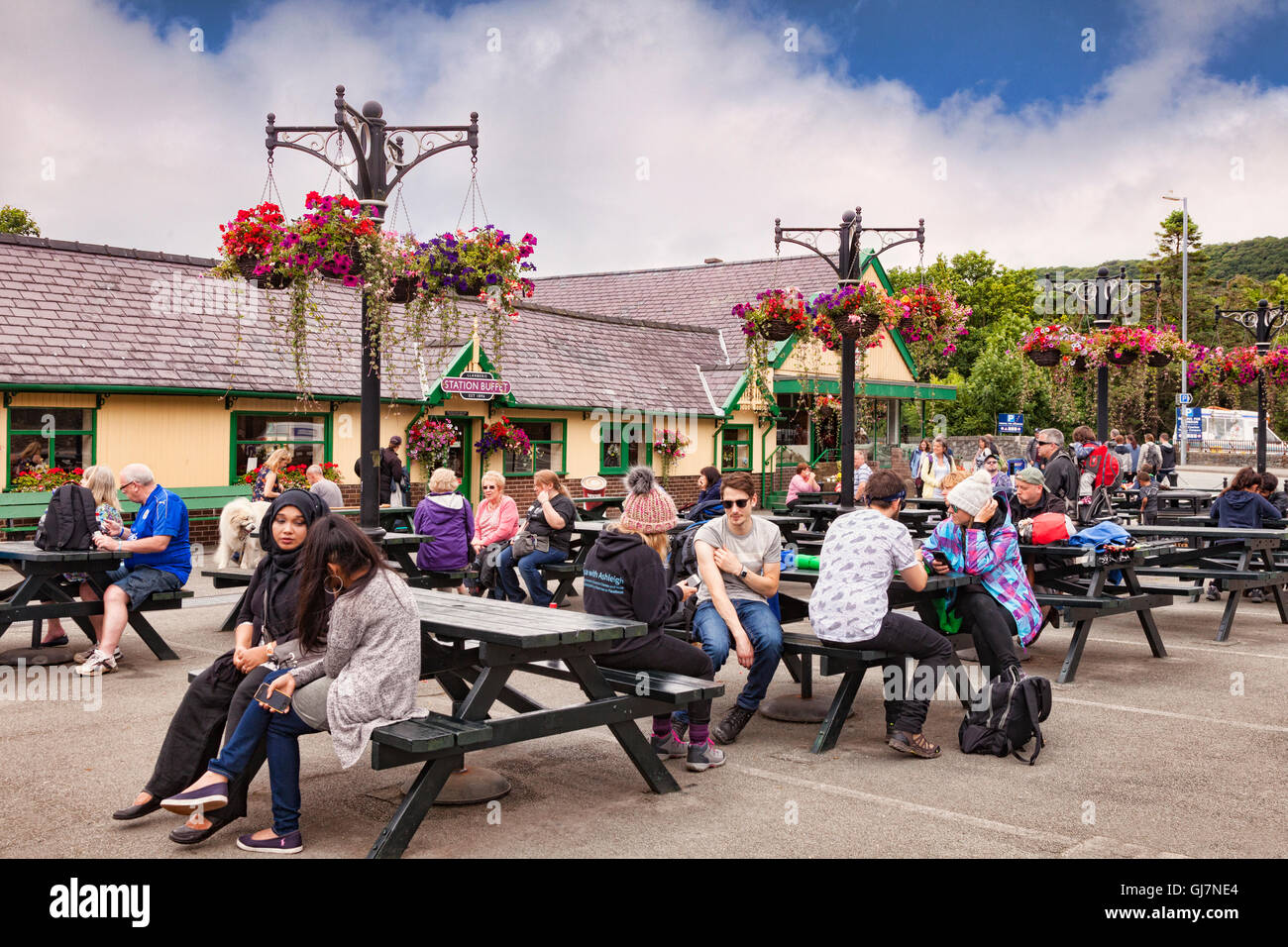 La gente seduta al di fuori del buffet della stazione a Llanberis Stazione, Parco Nazionale di Snowdonia, Gwynedd, Wales, Regno Unito Foto Stock
