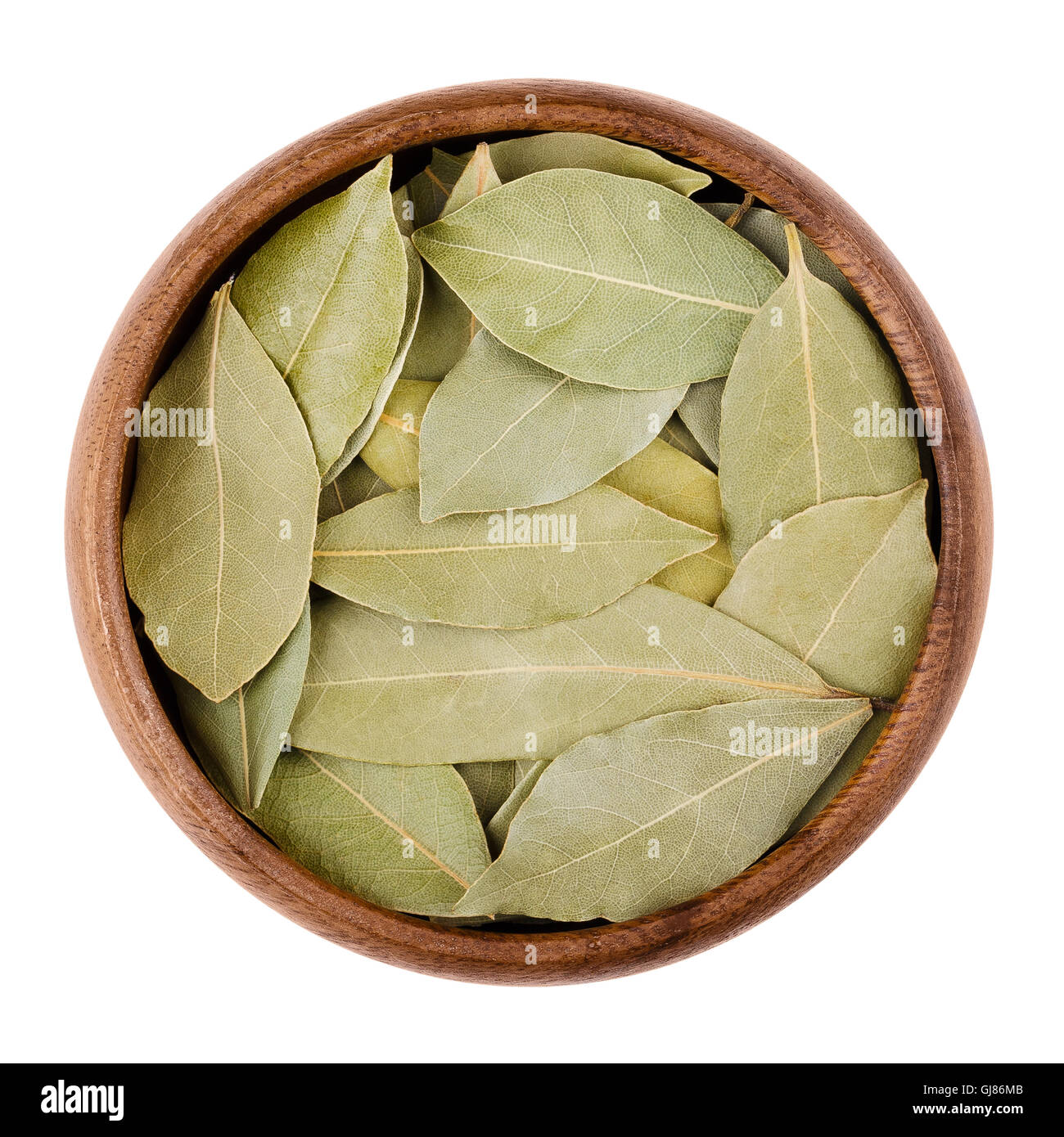 Essiccata foglie di alloro in una ciotola su bianco. Foglie aromatiche di Laurus nobilis, chiamato anche le foglie di alloro, utilizzati per la stagionatura in cottura. Foto Stock